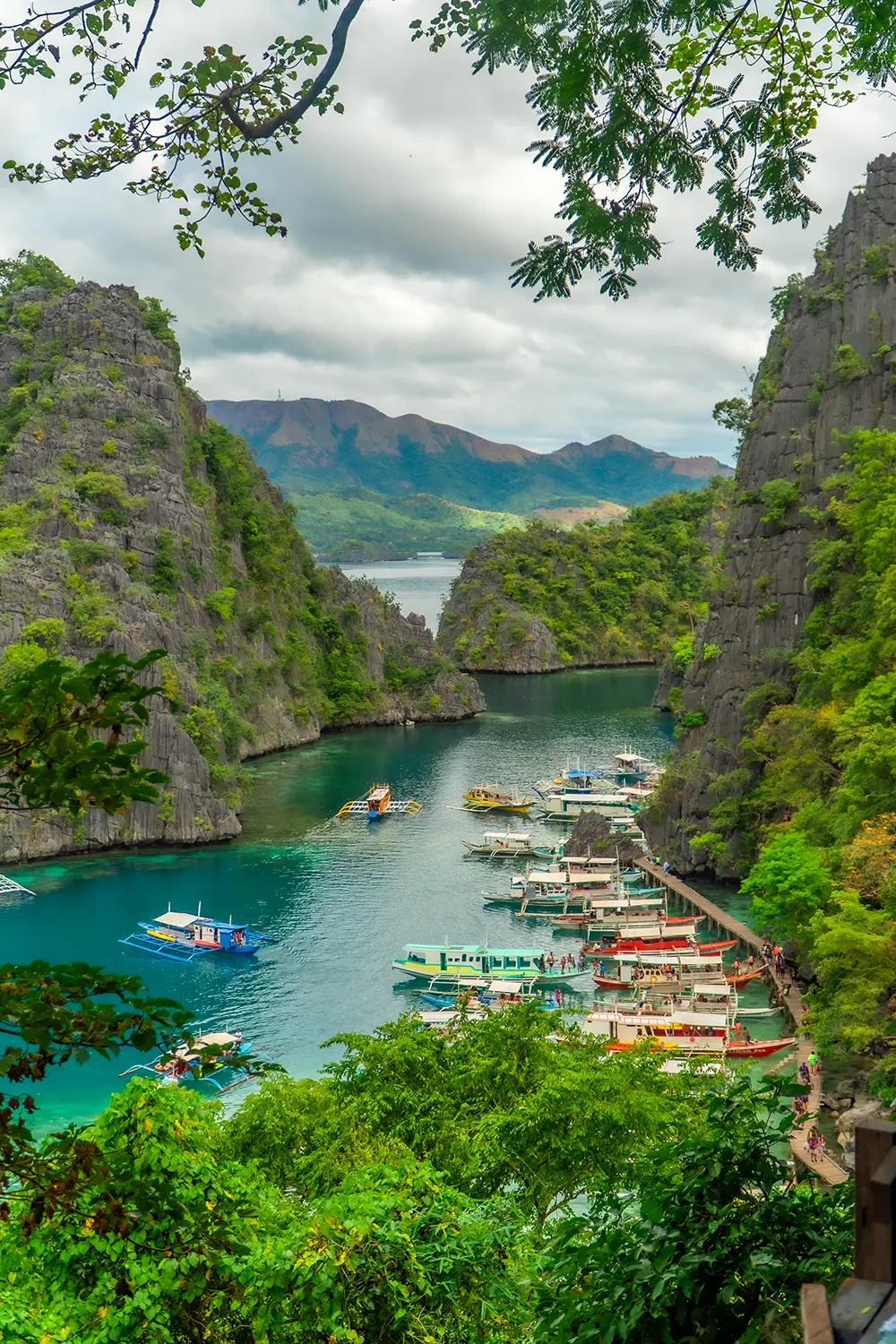 Tourists visiting Kayangan Lake on Coron Island, surrounded by limestone cliffs and clear water. The lake is accessible by boat as part of a standard island-hopping tour.